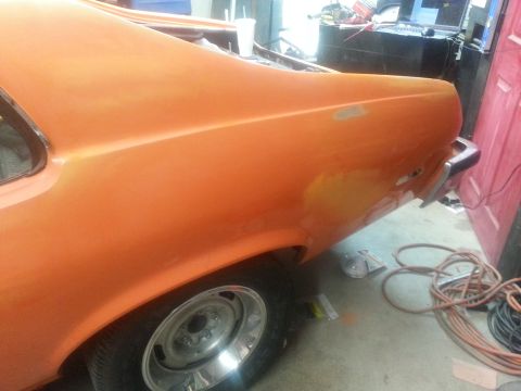 1973 Chevrolet Nova - The rear of an orange 1973 Chevrolet Nova is visible, undergoing bodywork in a garage.