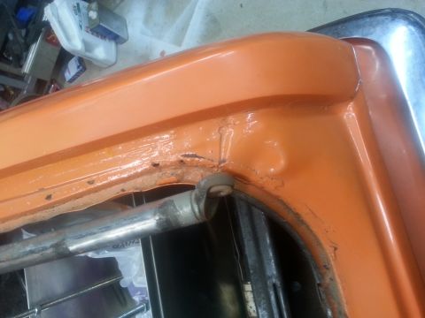 1973 Chevrolet Nova - Close-up of an orange painted metal part showing rust and a metal rod mechanism.