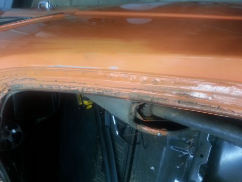 1973 Chevrolet Nova - Close-up of rust damage on the roof edge of an orange car, likely during restoration.