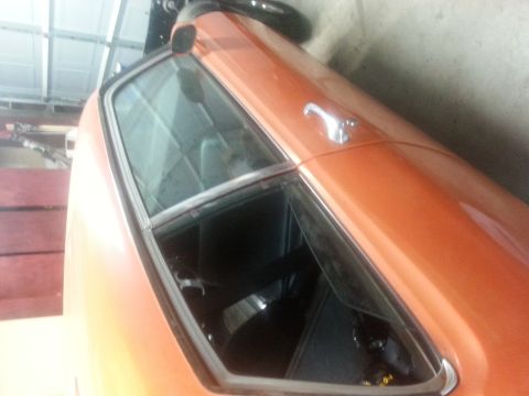1973 Chevrolet Nova - Close-up view of the interior and roof of an orange 1973 Chevrolet Nova, showing the driver's side window and door handle.