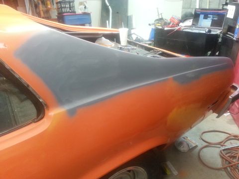 1973 Chevrolet Nova - The rear quarter panel of an orange 1973 Chevrolet Nova is shown with gray primer applied to a section, section being prepped for paint.