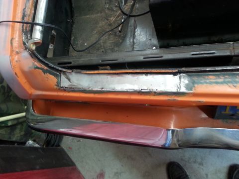 1973 Chevrolet Nova - The interior of a car's trunk shows exposed metal and a chrome bumper, indicating repair work.