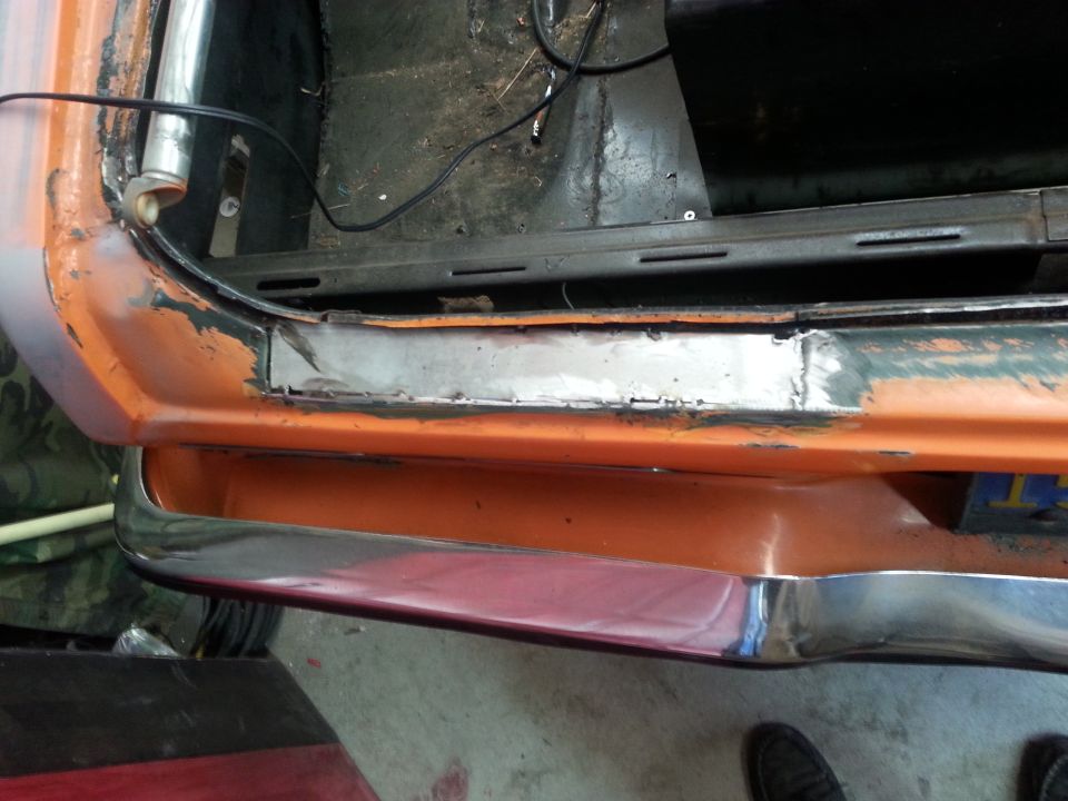 Orange car trunk interior with exposed metal and chrome bumper