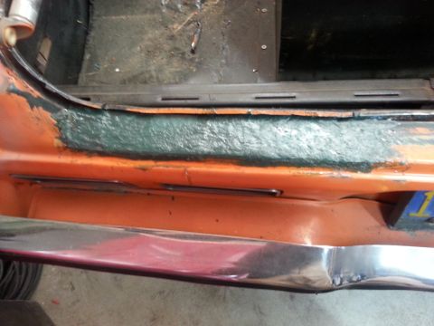 1973 Chevrolet Nova - The interior door sill area of an orange vehicle shows signs of repair and sealant application.