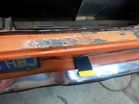 1973 Chevrolet Nova - Close-up of an orange car's front bumper showing signs of rust and damage.