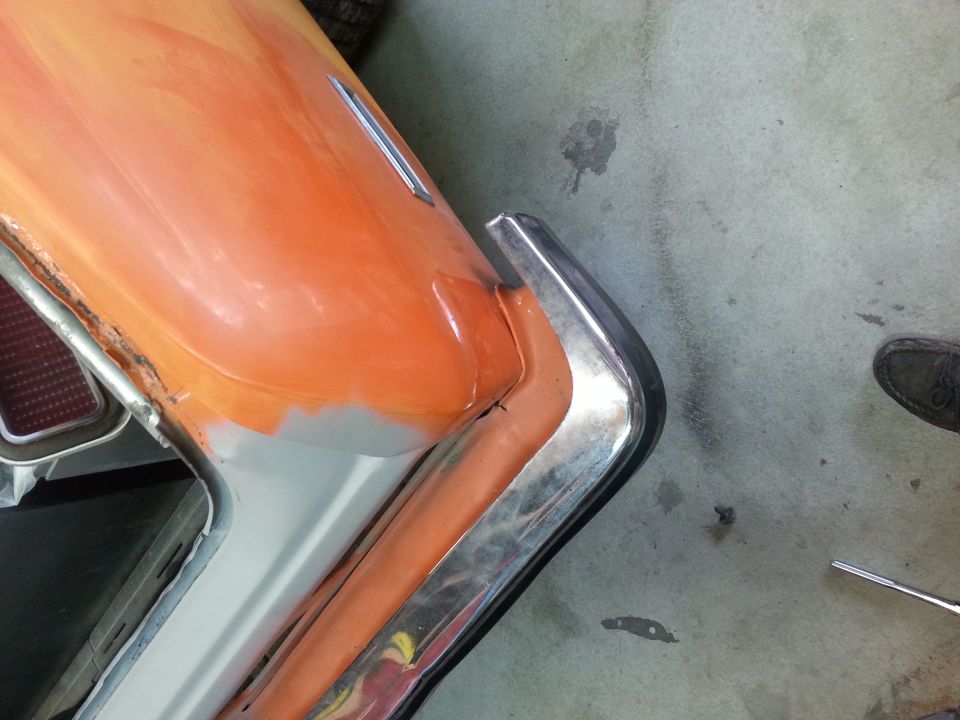car trunk area being prepped for paint, showing primer and some orange paint