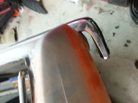 1973 Chevrolet Nova - Close-up of a car bumper being prepped for paint, showing primer and chrome trim.