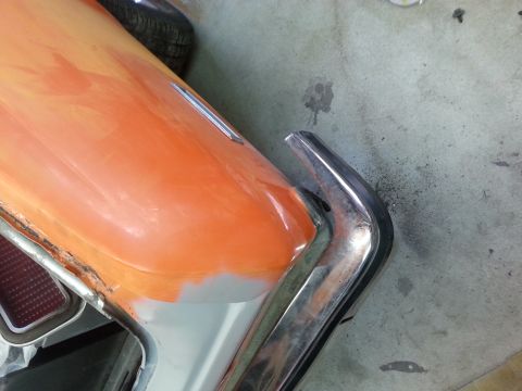 1973 Chevrolet Nova - Close-up of a car's rear corner, revealing primer and chrome trim during restoration.