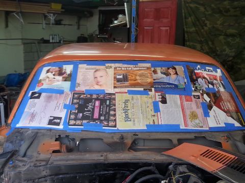 1973 Chevrolet Nova - Newspaper clippings are taped to the inside of a car's windshield, likely as a mask for painting.