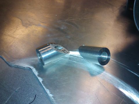 1995 Ford Probe - Two metal components sit on a workbench, one appears to be broken.