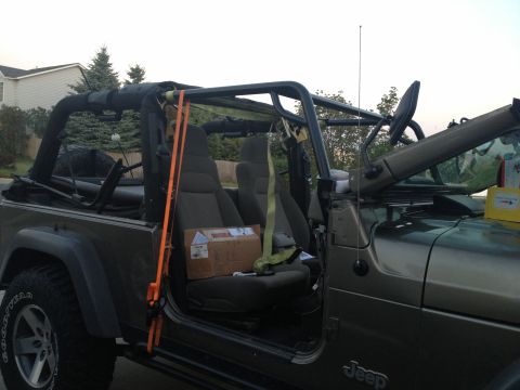 2005 Jeep Wrangler - The interior of a 2005 Jeep Wrangler shows an aftermarket roll cage and a box on the passenger seat.