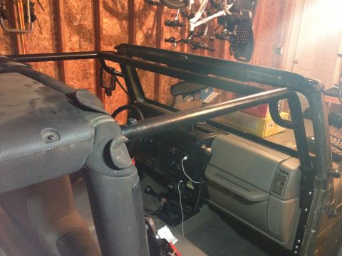 2005 Jeep Wrangler - The interior of a Jeep is shown, an aftermarket roll cage and dashboard.