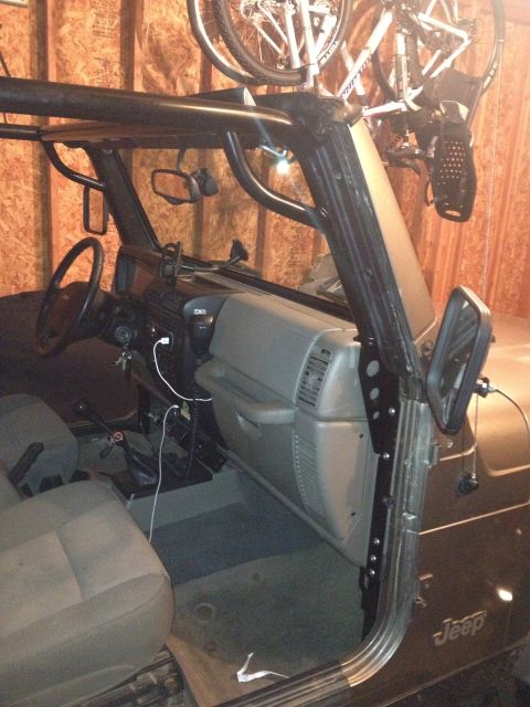 2005 Jeep Wrangler - Interior view of a Jeep Wrangler, showing the dashboard, seats, and a custom roll cage, with bicycles stored above.