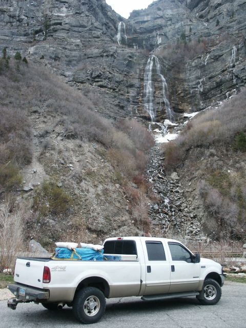2000 Ford F-250 - A Ford F-250 pickup truck is parked in front of a large waterfall cascading down a rocky mountainside.