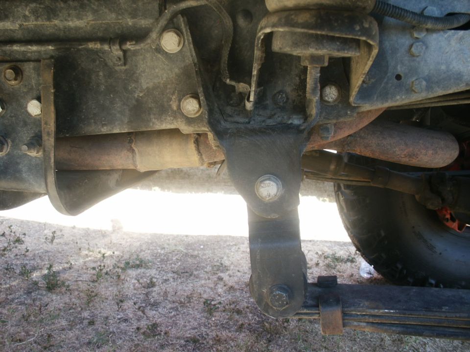 Undercarriage view of truck suspension with leaf springs and exhaust pipe. Supermotors.net logo visible