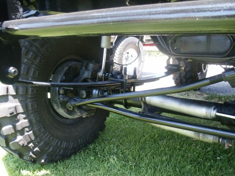 2000 Ford F-250 - Close-up view of a truck's undercarriage, showing its heavy-duty suspension system and knobby tires.