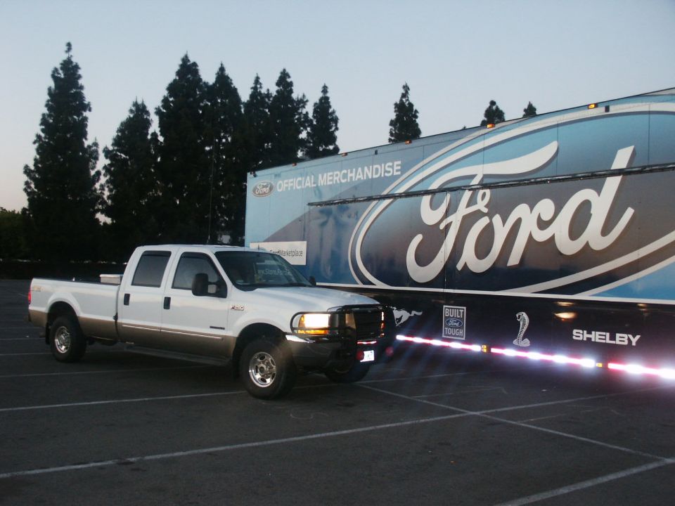 2000 Ford F-250 Super Duty Crew Cab pickup truck parked next to a Ford official merchandise trailer with Shelby branding