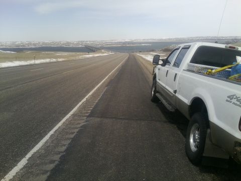 2000 Ford F-250 - White 2000 Ford F-250 parked on the shoulder of a highway, with a bridge and body of water visible in the distance.