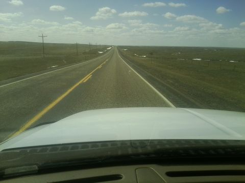 2000 Ford F-250 - A long stretch of highway unfolds across a vast, open landscape under a partly cloudy sky.