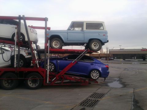2000 Ford F-250 - A light blue 1978 Ford Bronco is transported on a car carrier alongside other vehicles.