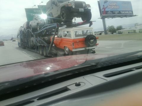 2000 Ford F-250 - An orange Ford Bronco is transported on a car carrier alongside other vehicles on the highway.