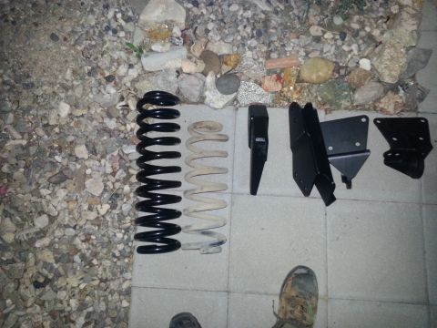 1991 Ford Bronco - Suspension lift kit parts including coil springs and various brackets are displayed on a concrete surface.