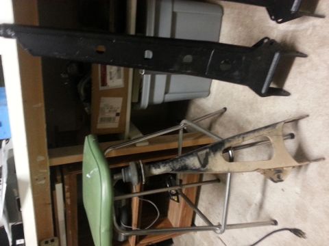 1991 Ford Bronco - Two vehicle suspension parts are visible, one black and one tan, resting on shelving.