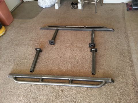 1991 Ford Bronco - Uninstalled metal side steps and their mounting hardware are displayed on a carpeted surface.