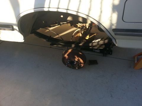 1991 Ford Bronco - The rear suspension of a vehicle is visible with the wheel removed, showing leaf springs and the brake drum.