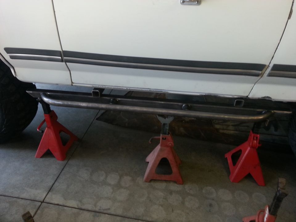 White SUV side view with custom metal side steps mounted on red jack stands