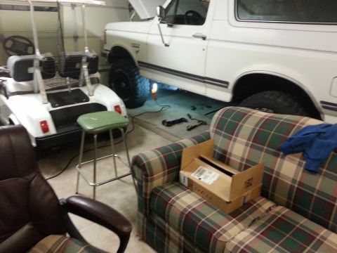 1991 Ford Bronco - White 1991 Ford Bronco in a garage, with a golf cart and furniture nearby.