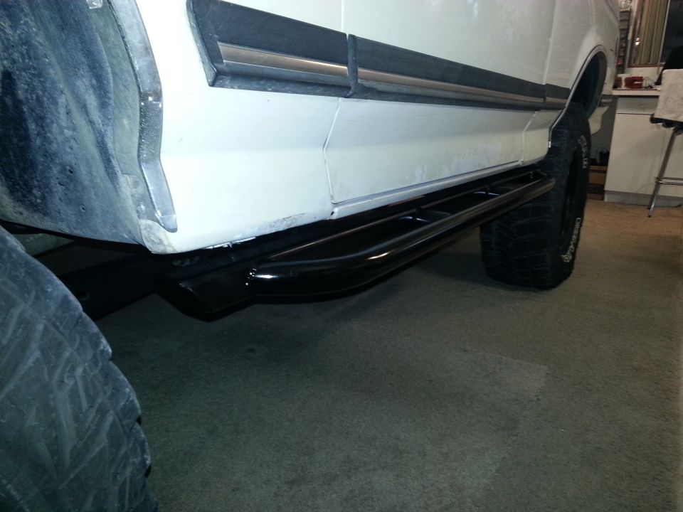 Side view of black tubular side step bars on a white 1991 Ford Bronco