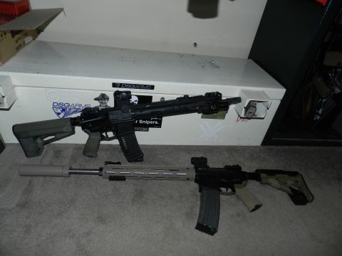 1996 Ford Bronco - Two rifles are displayed on a carpet in front of a gun safe. One rifle has a suppressor attached.