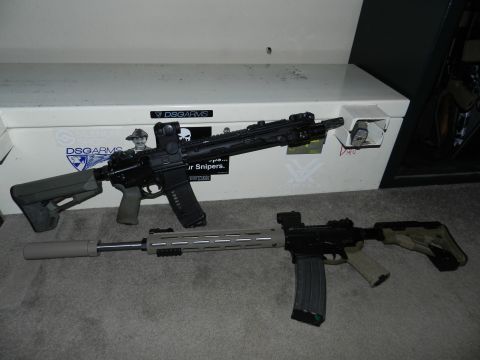 1996 Ford Bronco - Two rifles, one with a suppressor, rest on a carpet in front of a safe with various stickers.