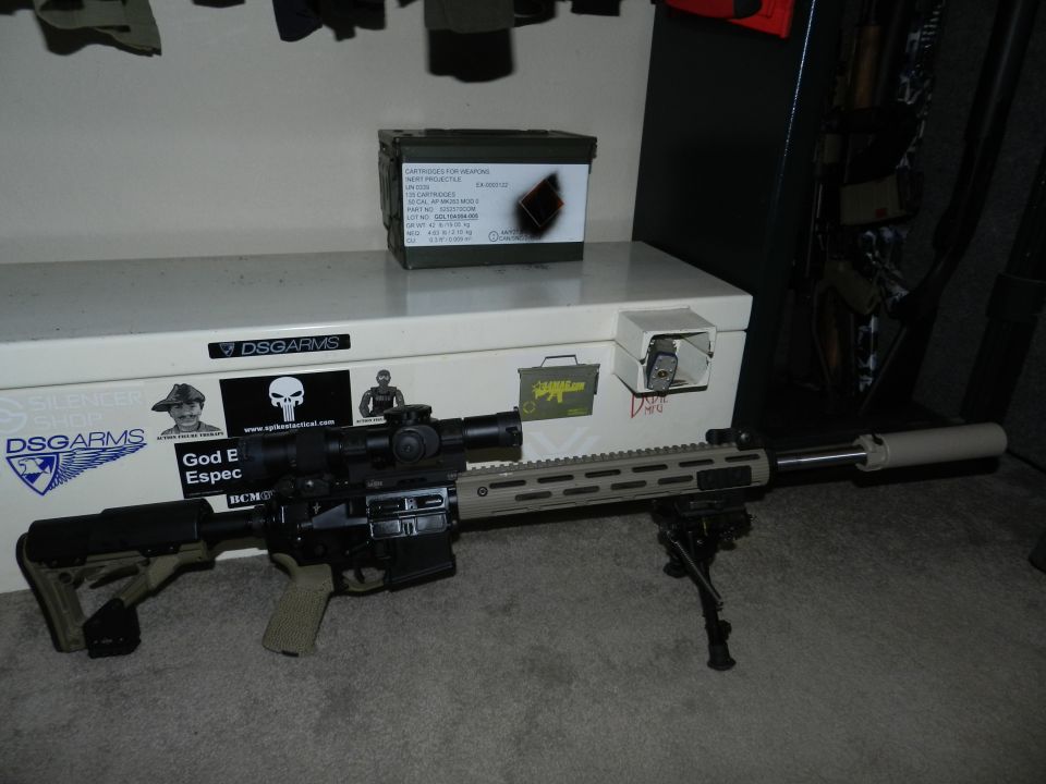 AR-15 style rifle with scope, bipod, and suppressor, resting on a storage box