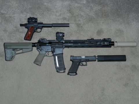 1996 Ford Bronco - Three firearms, including an AR-15 style rifle and two pistols, are displayed with suppressors attached.