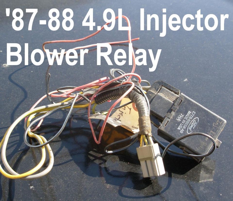 Black Ford relay with wiring harness and gray connector on dark surface
