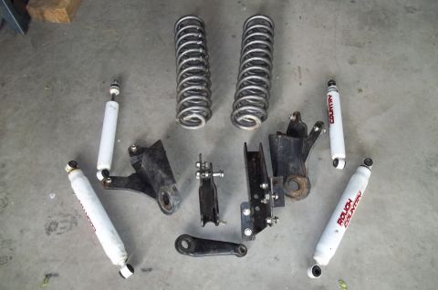 1990 Ford Bronco - Various suspension components, including shocks and springs, are arranged on a flat surface.