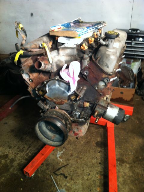 1996 Ford Bronco - This engine is mounted on an orange stand, with a book placed on top of it.