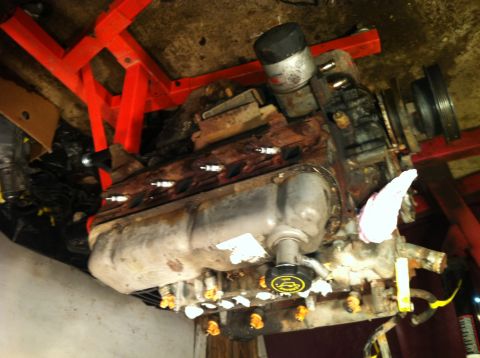 1996 Ford Bronco - Engine on a stand, viewed from below, showing its V8 configuration and rusty condition.