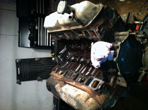 1996 Ford Bronco - Close-up view of a used engine block, showing signs of wear and oil. The "Ford" logo is visible on the oil pan.