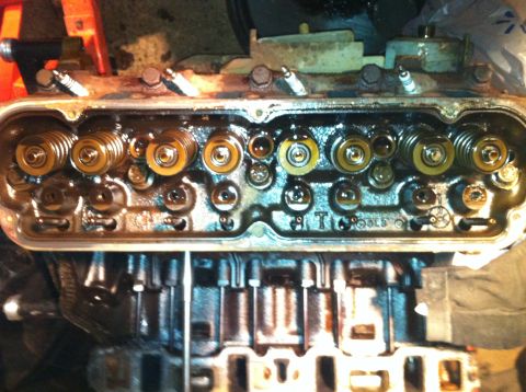1996 Ford Bronco - Close-up view of an engine's cylinder head, showing the valves and spark plug holes. The word 'TOOLS' is stamped on the metal component.