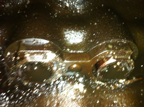 1996 Ford Bronco - Close-up view of the inside of an engine oil pan, showing oil and debris.