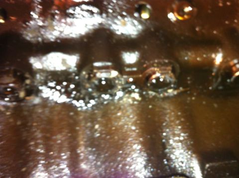 1996 Ford Bronco - The oil pan shows signs of wear and tear, with debris accumulated within.