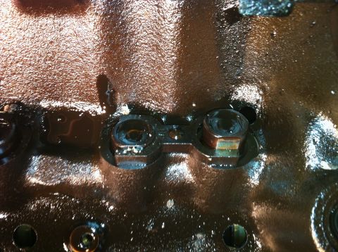1996 Ford Bronco - This image shows a close-up view of engine components, likely a part of an engine block, covered in oil and visible bolts.