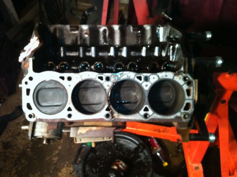 1996 Ford Bronco - Engine block with pistons is shown on an orange engine stand.