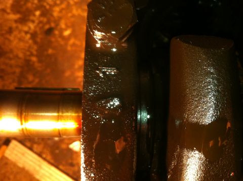 1996 Ford Bronco - Close-up view of an engine crankshaft, heavily coated in oil, with visible reflections on its surface.