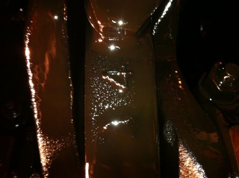 1996 Ford Bronco - Close-up of dark, greasy metal frame parts, likely from a vehicle's undercarriage.