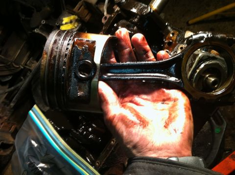 1996 Ford Bronco - Engine part being held by a hand, covered in oil and grime.