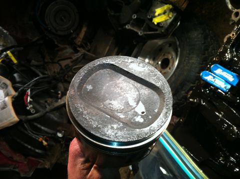 1996 Ford Bronco - A close-up view of a used piston, showing significant wear and carbon deposits.
